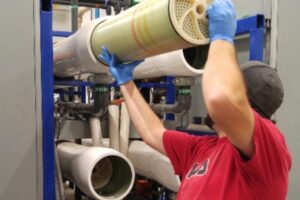 Technician installing reverse osmosis membrane in industrial RO system
